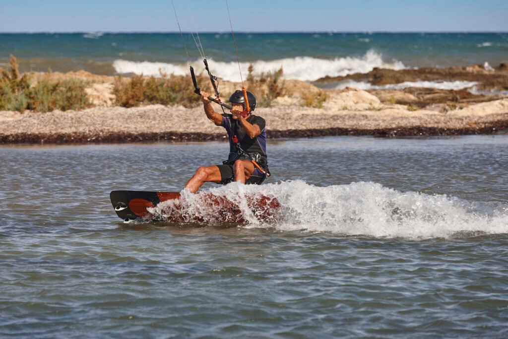 Mature man practicing kitesurfing. Aquatic sport. Athletic healthy senior male