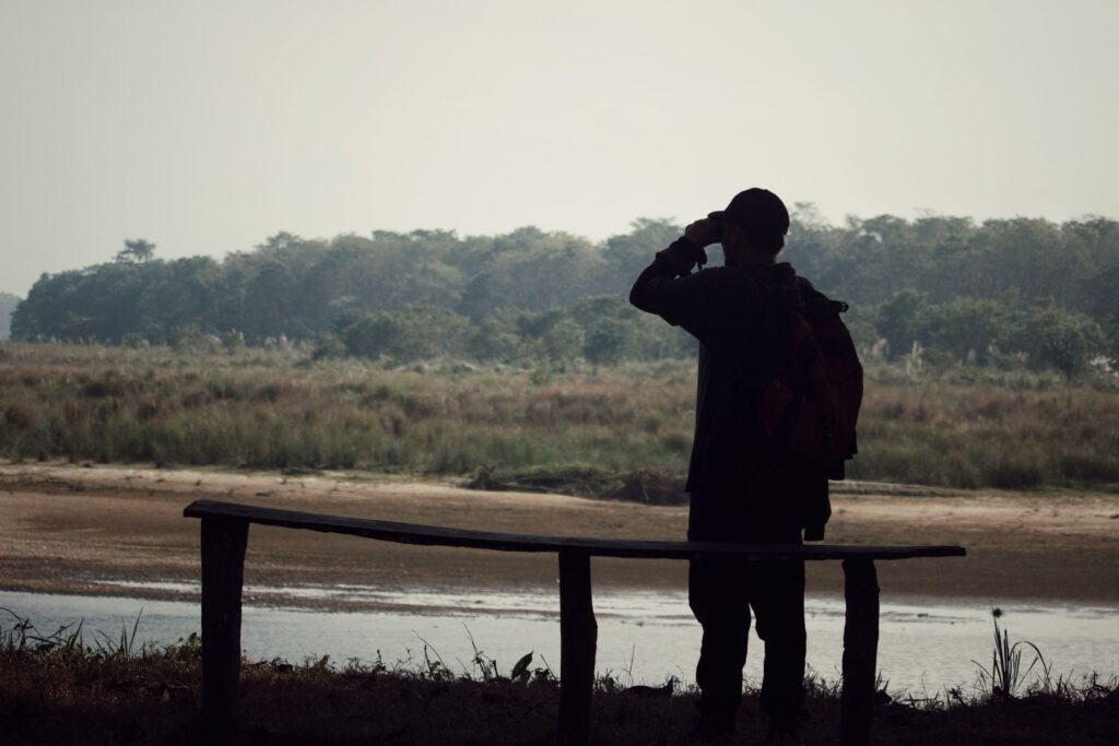 Birdwatcher using binoculars beside a wetland landscape