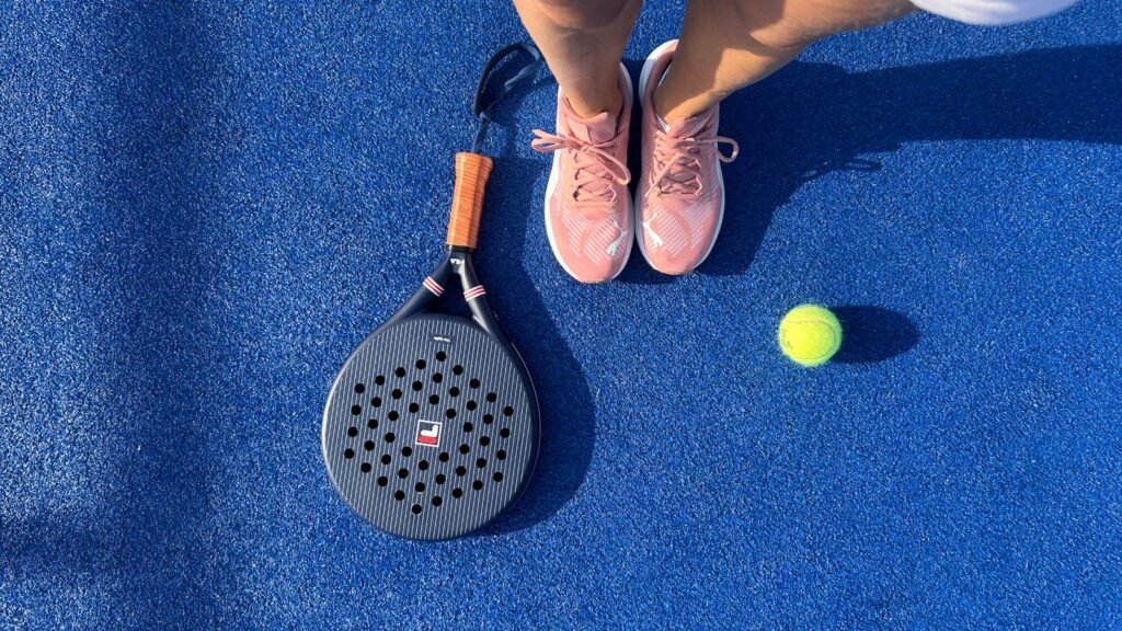 Padel player with racket and ball on a blue court
